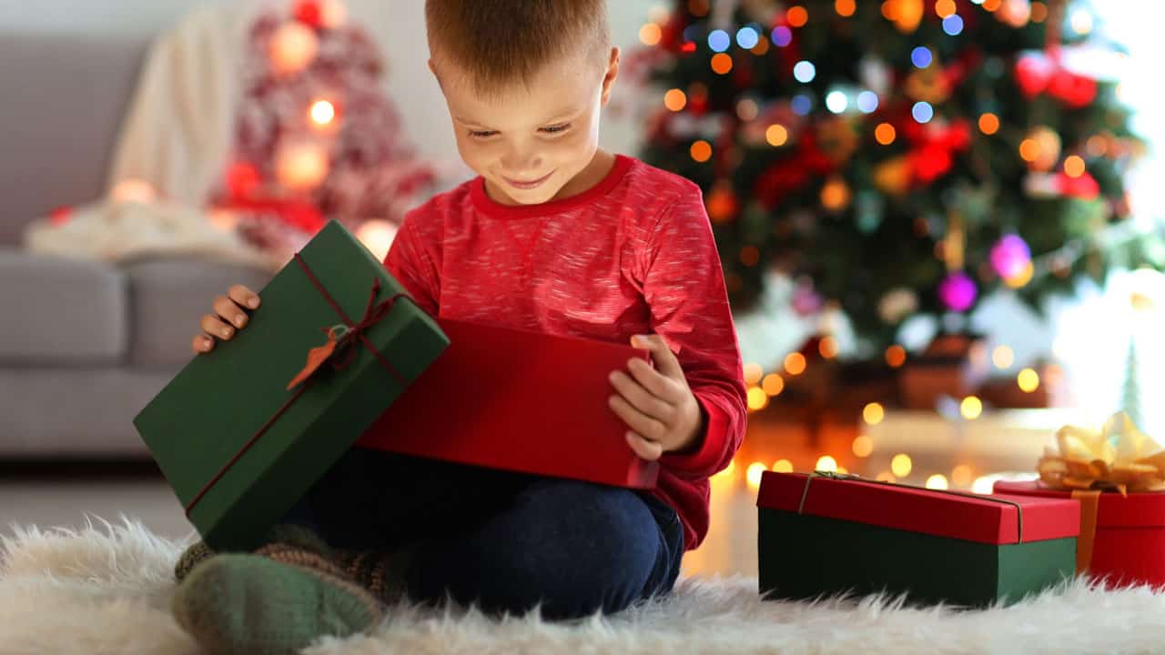 young boy smiling opening gift